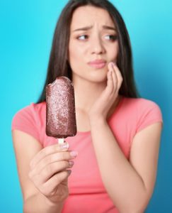 Une femme a les dents sensibles en mangeant un popsicle